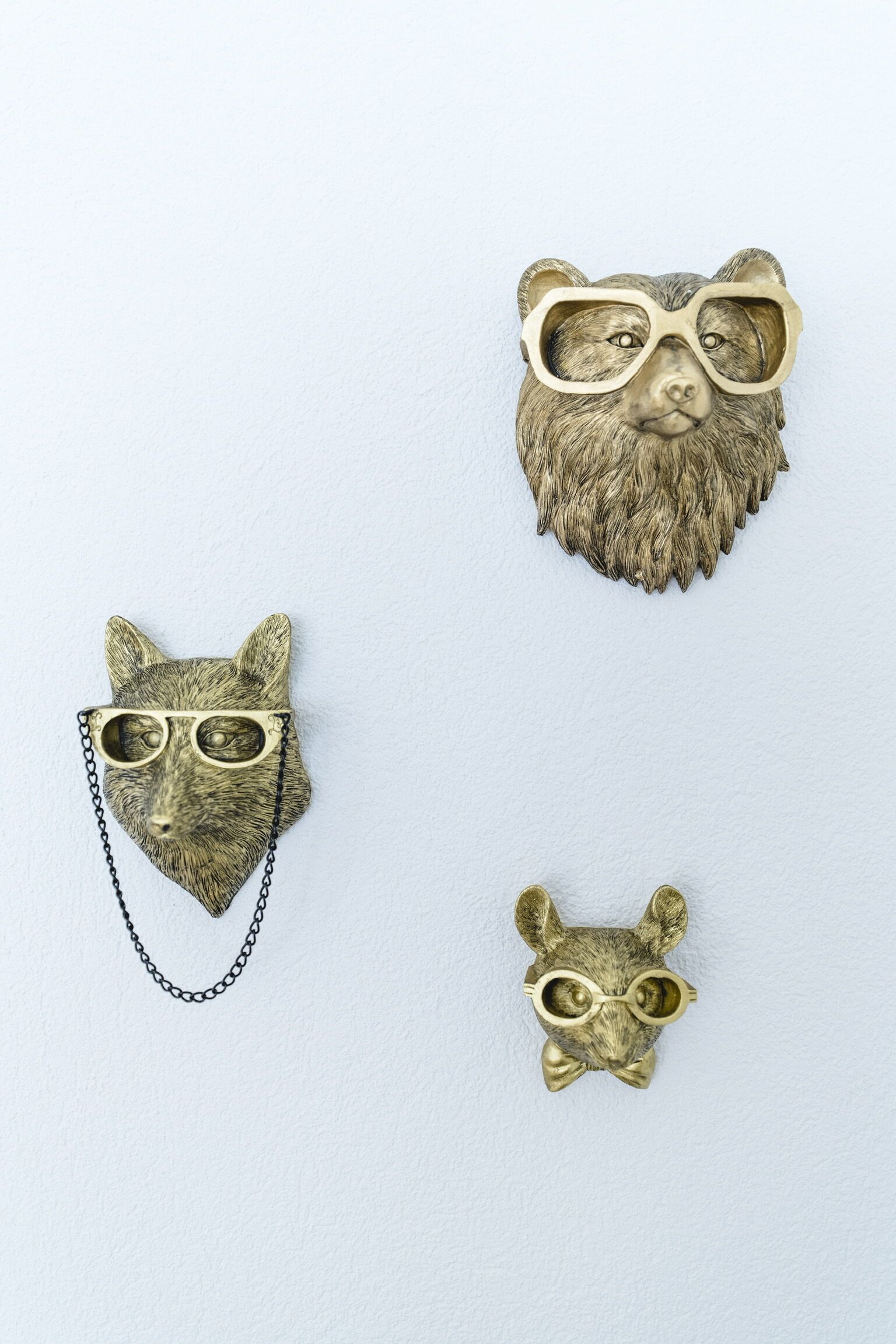 Trois décorations murales représentant des têtes d’animaux, chacune portant des lunettes.