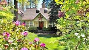 Una casa encantadora amb una estrella a la porta, envoltada de vegetació exuberant i plantes florides.