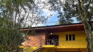 Une maison à deux étages avec une façade jaune, une porte en bois et un escalier menant à l’étage supérieur.