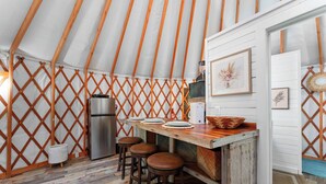 A cozy kitchen with a wooden table, stools, and a refrigerator.