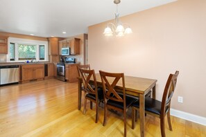 Une cuisine avec des meubles en bois, une cuisinière en acier inoxydable et une table à manger avec des chaises.