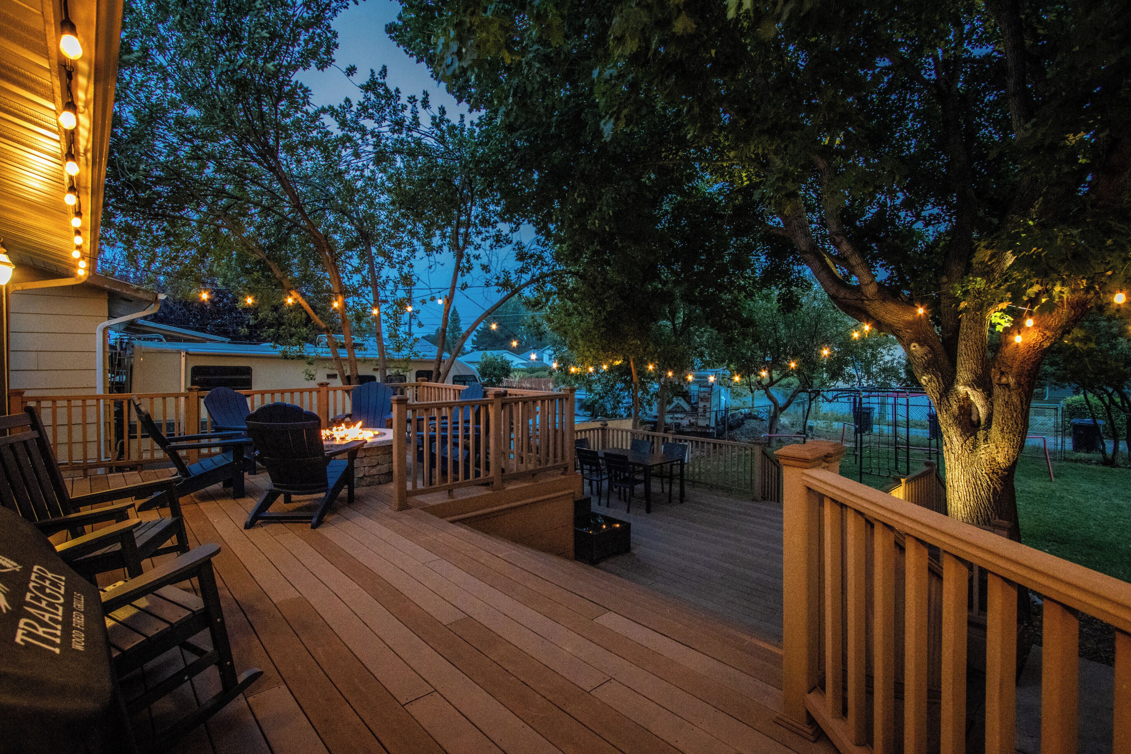 An outdoor deck with wooden flooring, outdoor furniture, and string lights.
