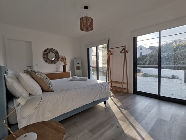 A modern bedroom with a large bed, a hanging chair, and a view of a snowy landscape through large windows.