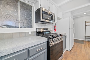 Una cocina con estufa de acero inoxidable, microondas y refrigerador.