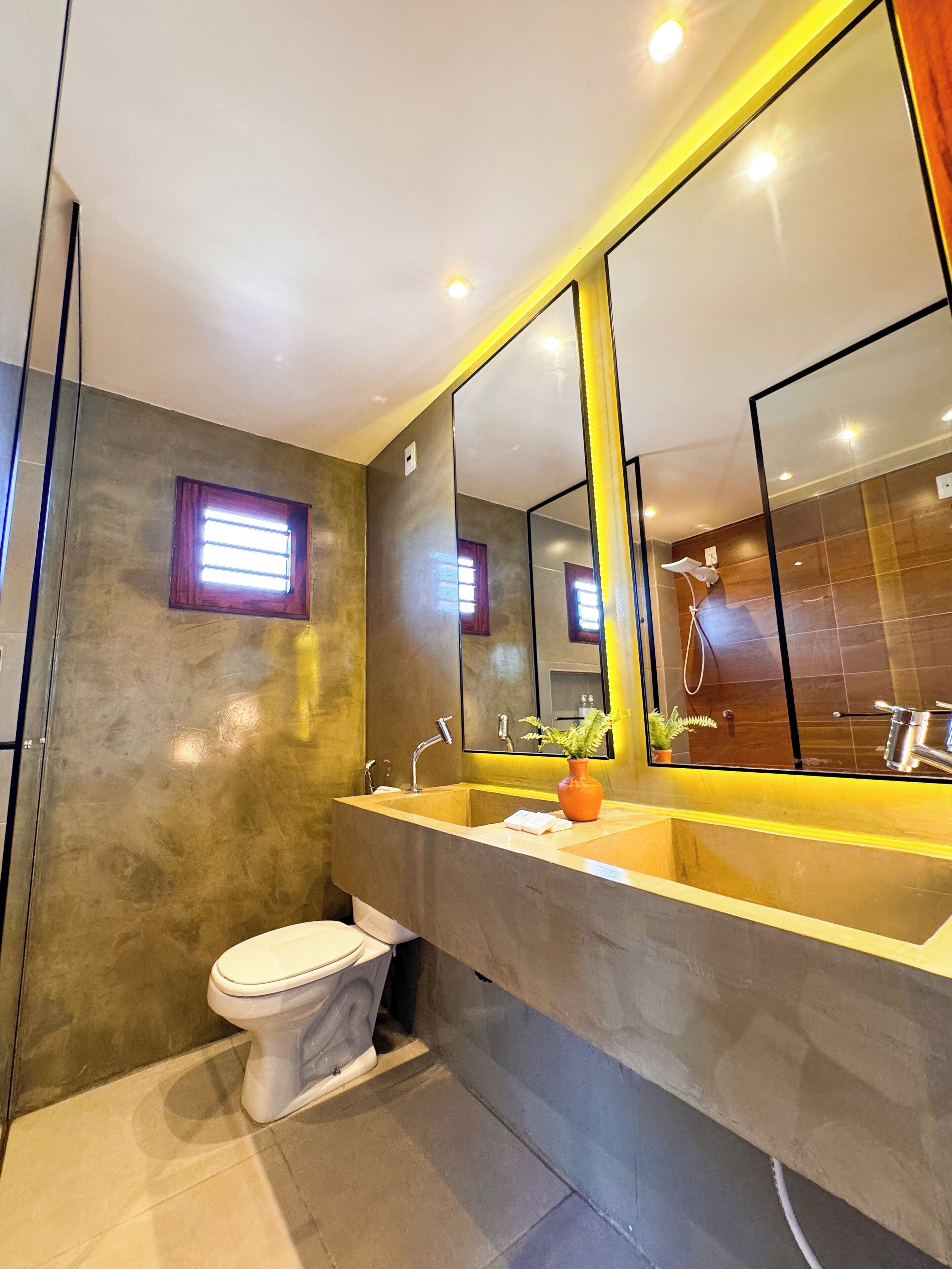 A modern bathroom with a large mirror, a sink, and a toilet.