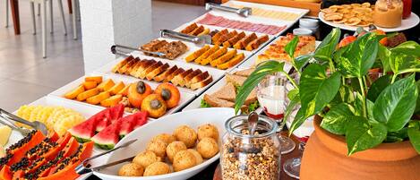 Ein Buffet mit verschiedenen Speisen, darunter Früchte, Gebäck und einer Pflanze.