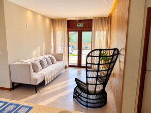 A hotel lobby with a sofa, a black woven chair, and a reception desk. - HOTEL ICARAI BEACH (Amontada)