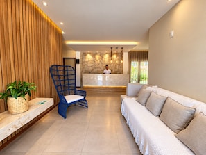 A hotel lobby with a reception desk, a blue chair, a sofa, and a potted plant. - HOTEL ICARAI BEACH (Amontada)