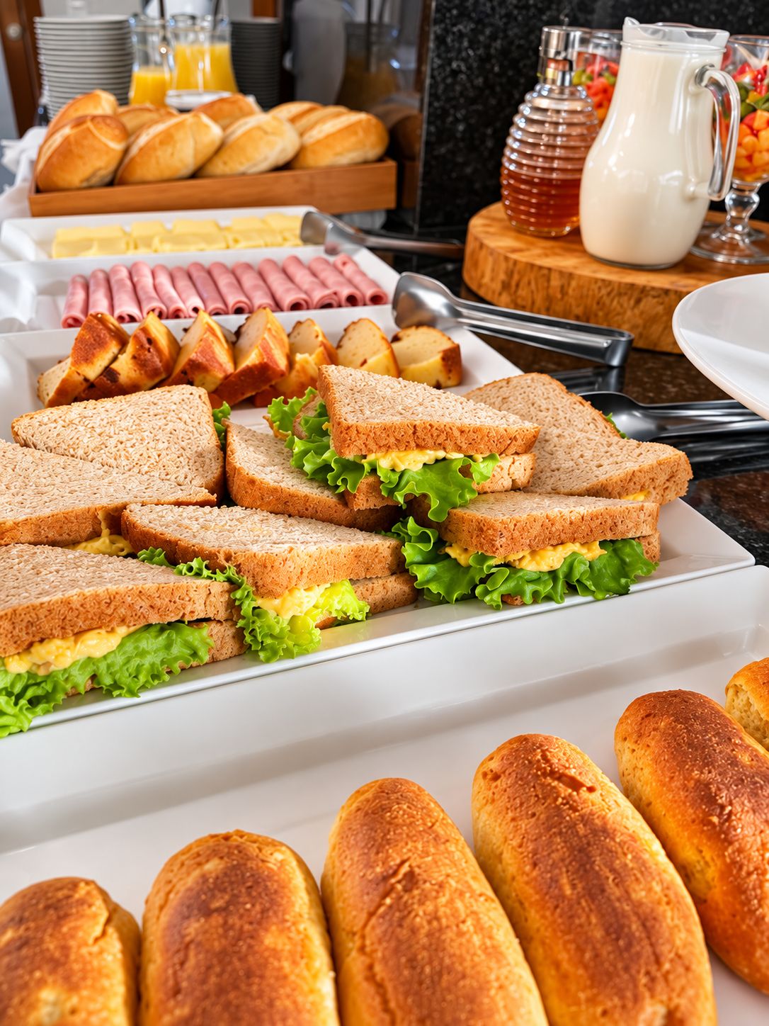 Un bufé de desayuno con sándwiches, panecillos y diferentes acompañamientos.