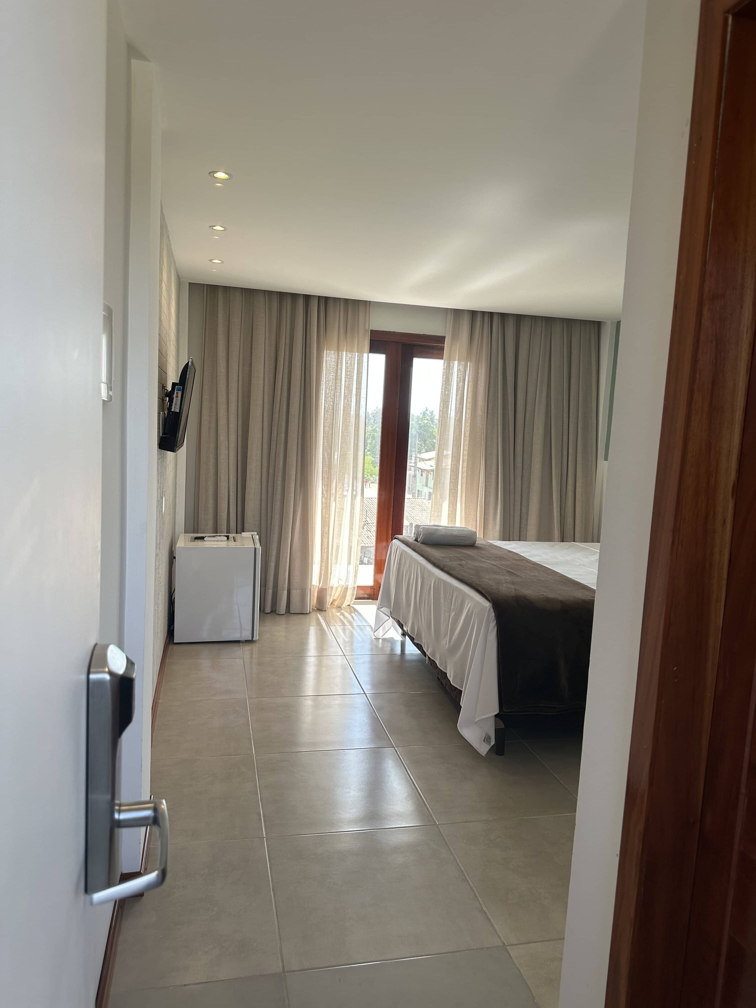 A hotel room with a bed, a desk, a chair, and a window with curtains.