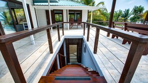 A wooden staircase leading to a covered outdoor area with a bench and chairs. - Picture-Perfect 2-Bedroom Oceanfront Home w/ Pool (Placencia)