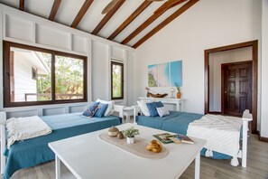 Une chambre moderne avec deux lits bleus, une table blanche et un plafond en bois.