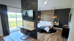 A modern bedroom with a bed, a TV mounted on a wall, a desk, and a chair.