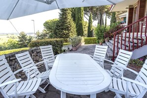 Un patio con una mesa y sillas blancas, un muro de piedra y una escalera roja.