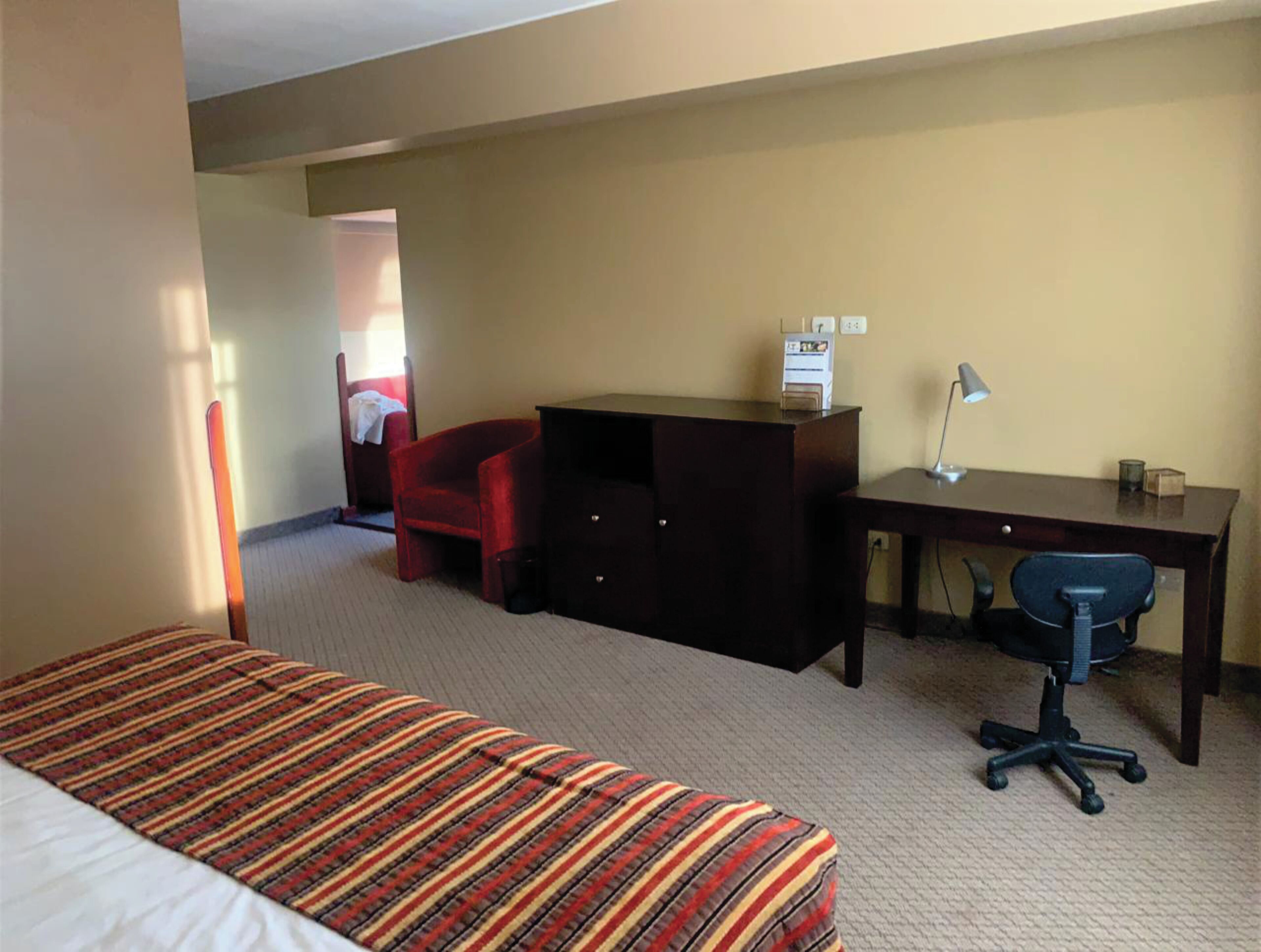 Una habitación de hotel con una cama, un escritorio, una silla y una mesita.