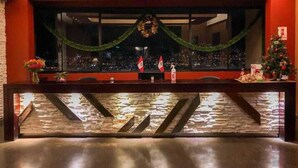 A reception area with a counter, a large window, and a Christmas tree. - Apu Mountain Lodge (Cusco)