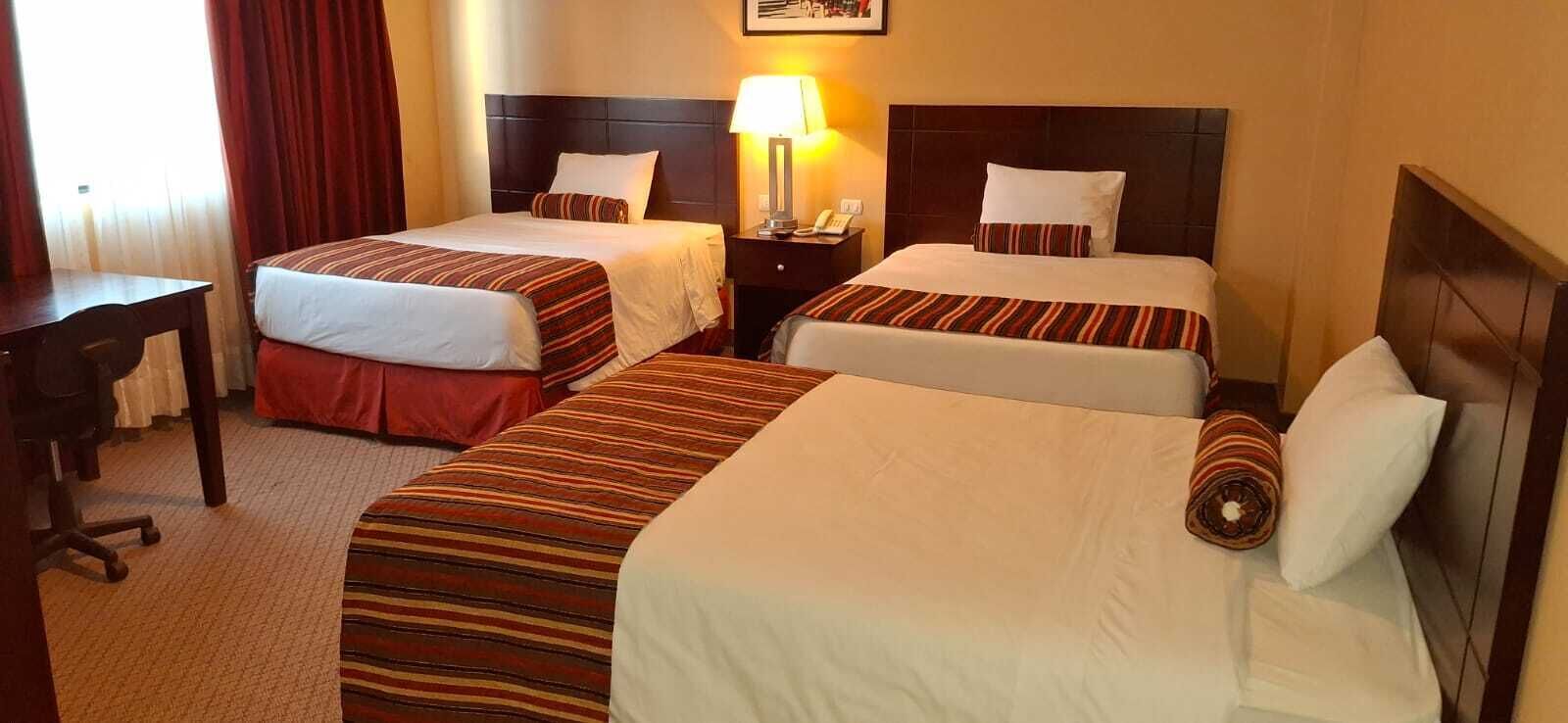A hotel room with two single beds, a desk, and a chair.