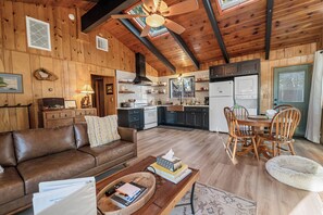A cozy cabin interior with a living room, dining area, and kitchen.