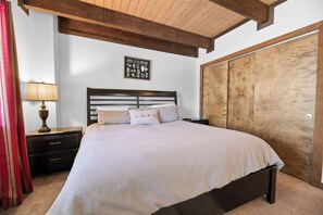 A bedroom with a bed, nightstand, lamp, and a wooden wardrobe. - Treetop Falls (Big Bear Lake)