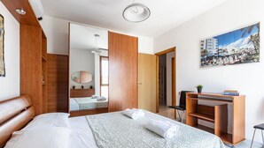 Ein Hotelzimmer mit einem Bett, einem Schreibtisch, einem Sessel, einem Spiegel und einem Bild an der Wand.