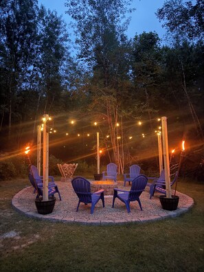 An outdoor seating area with Adirondack chairs, a fire pit, and string lights. - The Hidden Oasis, Duplex A. Close to almost everything! (Enfield)