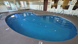 An indoor swimming pool with a 3 FT depth marker, surrounded by white chairs and a tiled wall with checkered patterns. - Toppenish Inn and Suites (Toppenish)