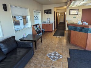 A hotel lobby with a reception desk, a seating area with a couch and a table, a bulletin board, and a tiled floor. - Toppenish Inn and Suites (Toppenish)