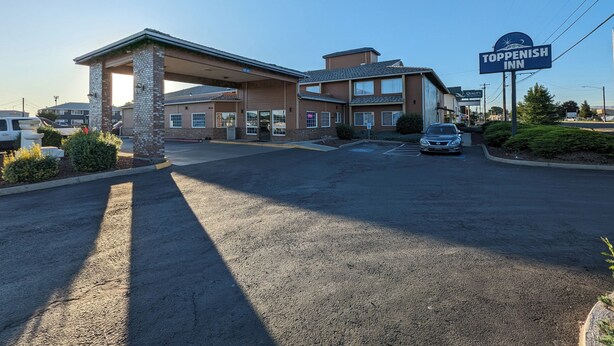 A Toppenish Inn with a covered parking area, a signboard, and a building with multiple windows.