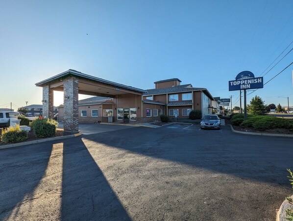 A Toppenish Inn with a covered parking area, a signboard, and a building with multiple windows.