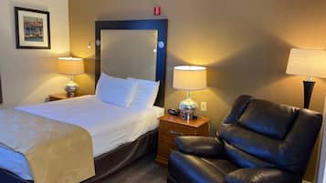 A hotel room with a bed, two bedside lamps, a black leather chair, and a wooden nightstand.