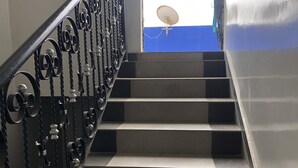 Een trap met zwart-witte treden en versierde metalen leuningen.