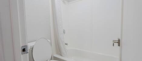 A bathroom with a toilet, a bathtub, and a shower curtain.