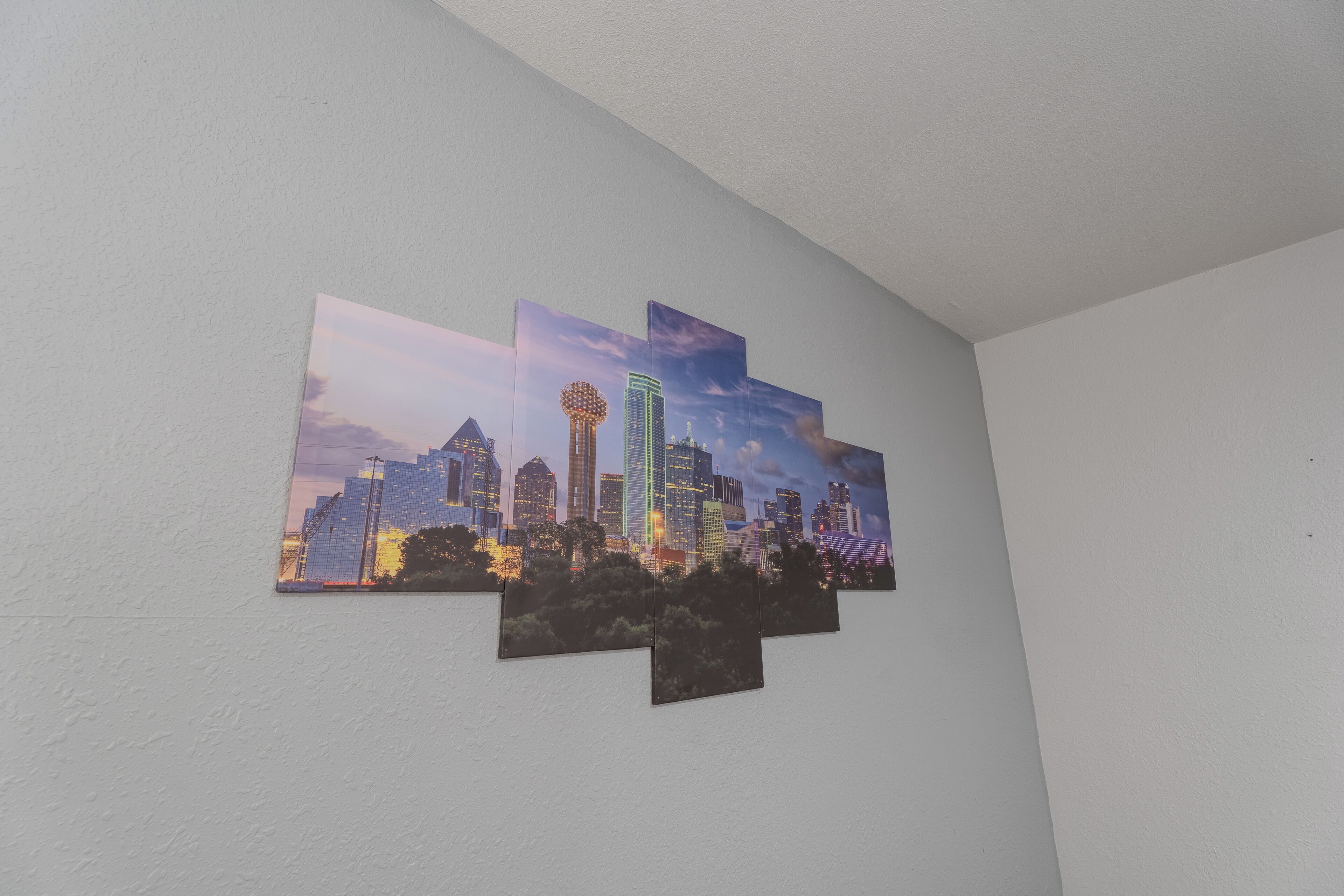 Een muur met een stadsgezicht kunstwerk, met hoge gebouwen en een opvallende toren.