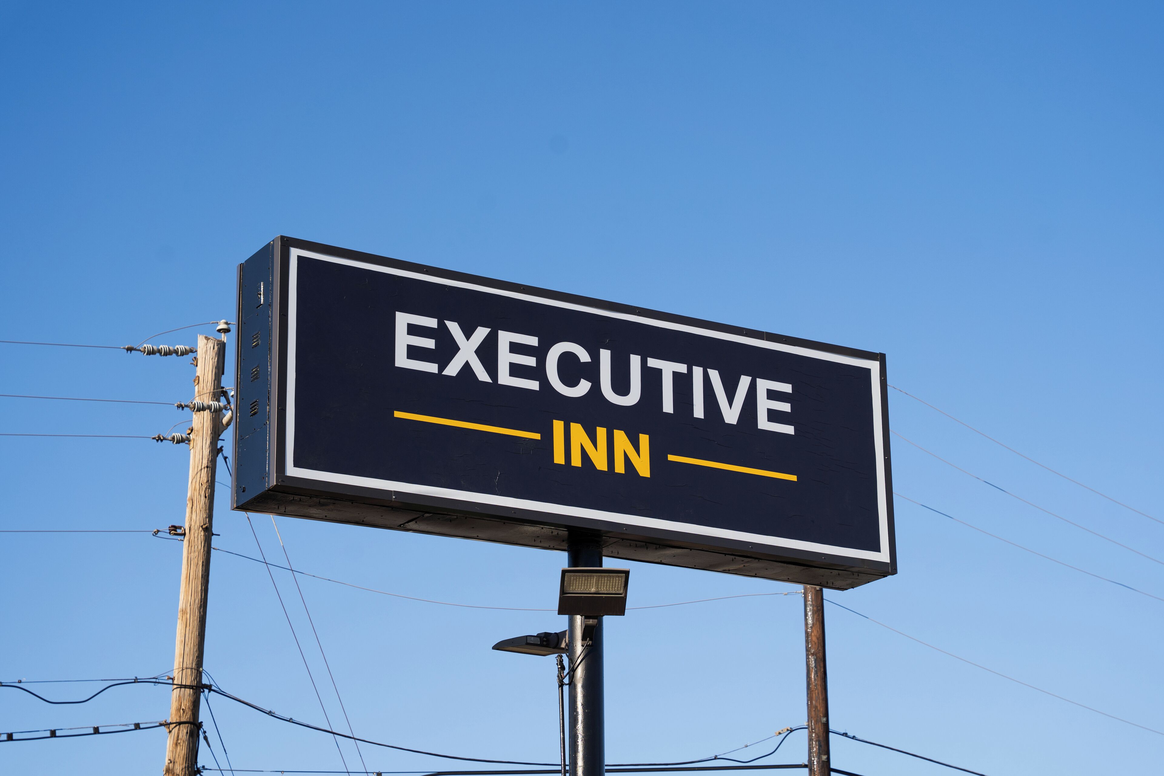 A billboard with the text 'EXECUTIVE INN' against a clear blue sky.
