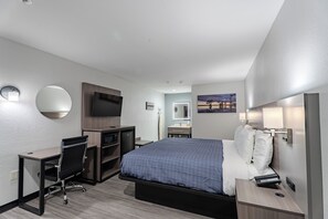 Une chambre d’hôtel avec un lit, un bureau, une chaise, une télévision et un tableau au mur.
