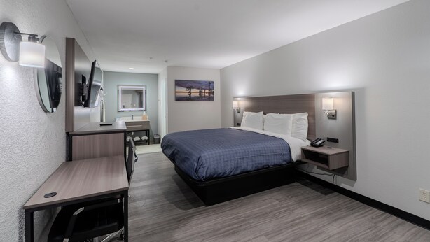 Ein modernes Hotelzimmer mit einem großen Bett, einem Schreibtisch, einem Sessel und einem kleinen Tisch.