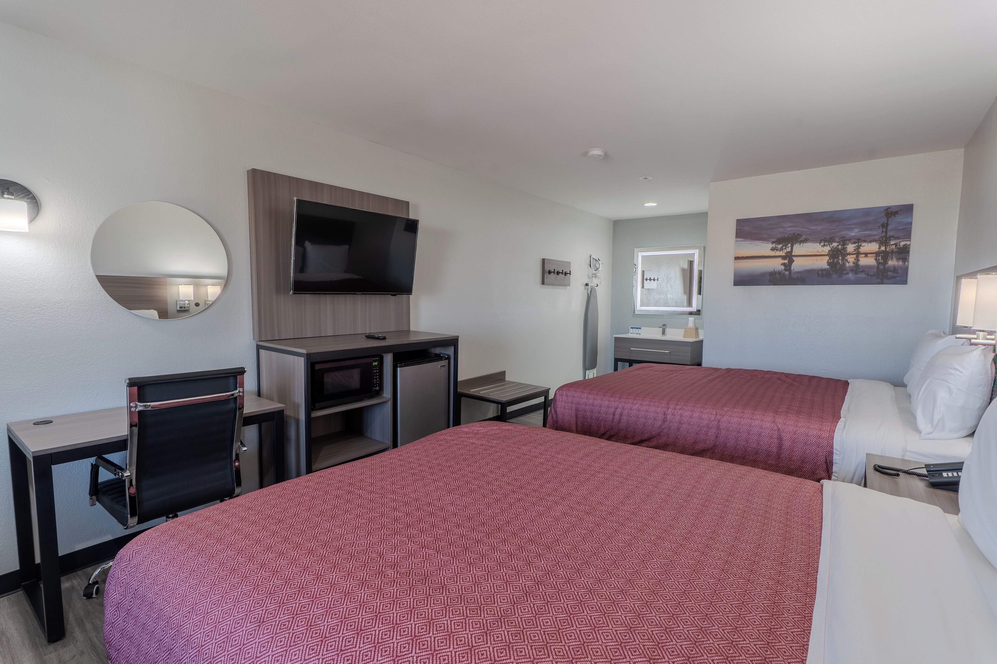 Hotelkamer met twee bedden, een bureau, een flatscreen televisie, een magnetron, een kleine tafel en een stoel.