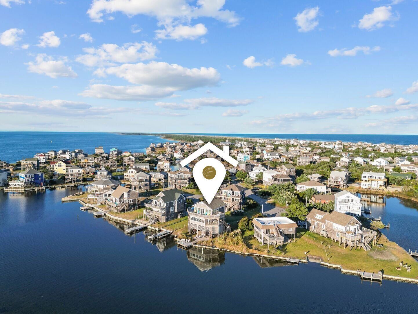 Vue aérienne d’un quartier résidentiel situé au bord de l’eau, avec des maisons, des quais et un ciel dégagé.