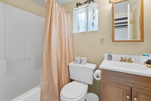 Une salle de bain équipée de toilettes, d’un rideau de douche, d’un lavabo et d’un miroir.