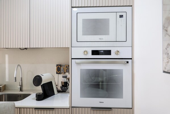 A kitchen with a microwave, oven, and coffee maker on a white countertop.