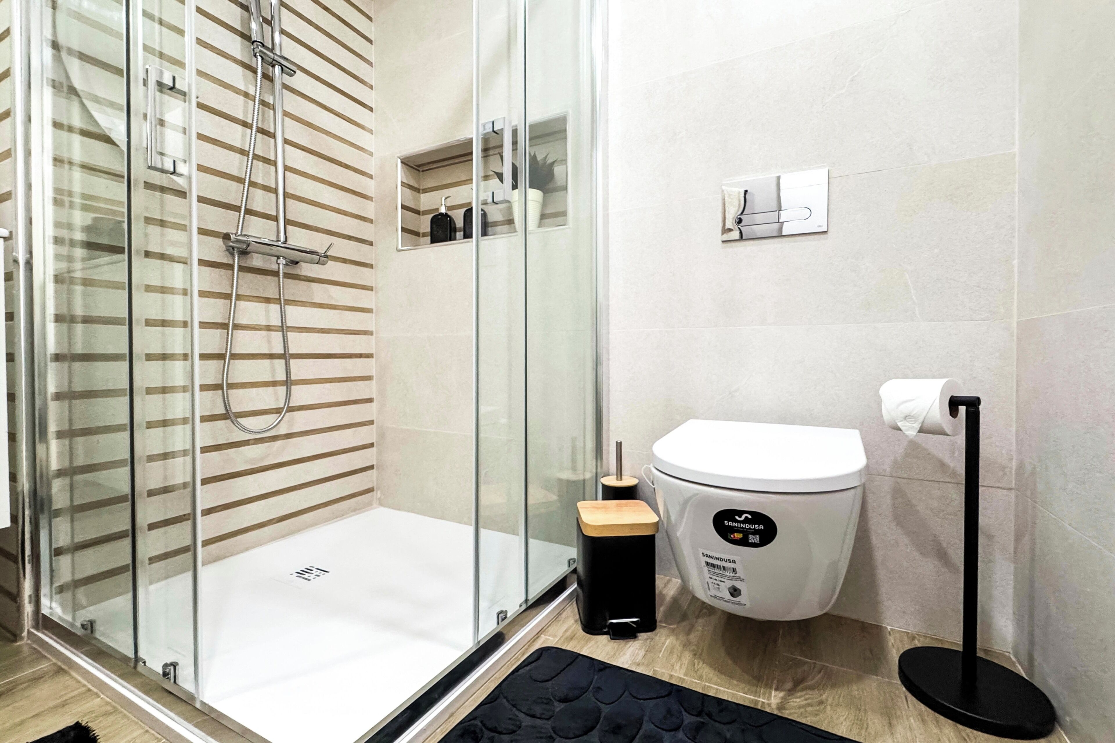 Une salle de bain moderne dotée d’une douche à parois de verre, de toilettes et d’un porte-serviettes.