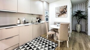 A modern kitchen with built-in appliances, a dining area with a round table and chairs, and a decorative plant.
