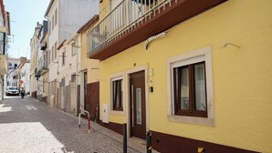 A cobblestone street lined with buildings, a door with a sign, and bollards.