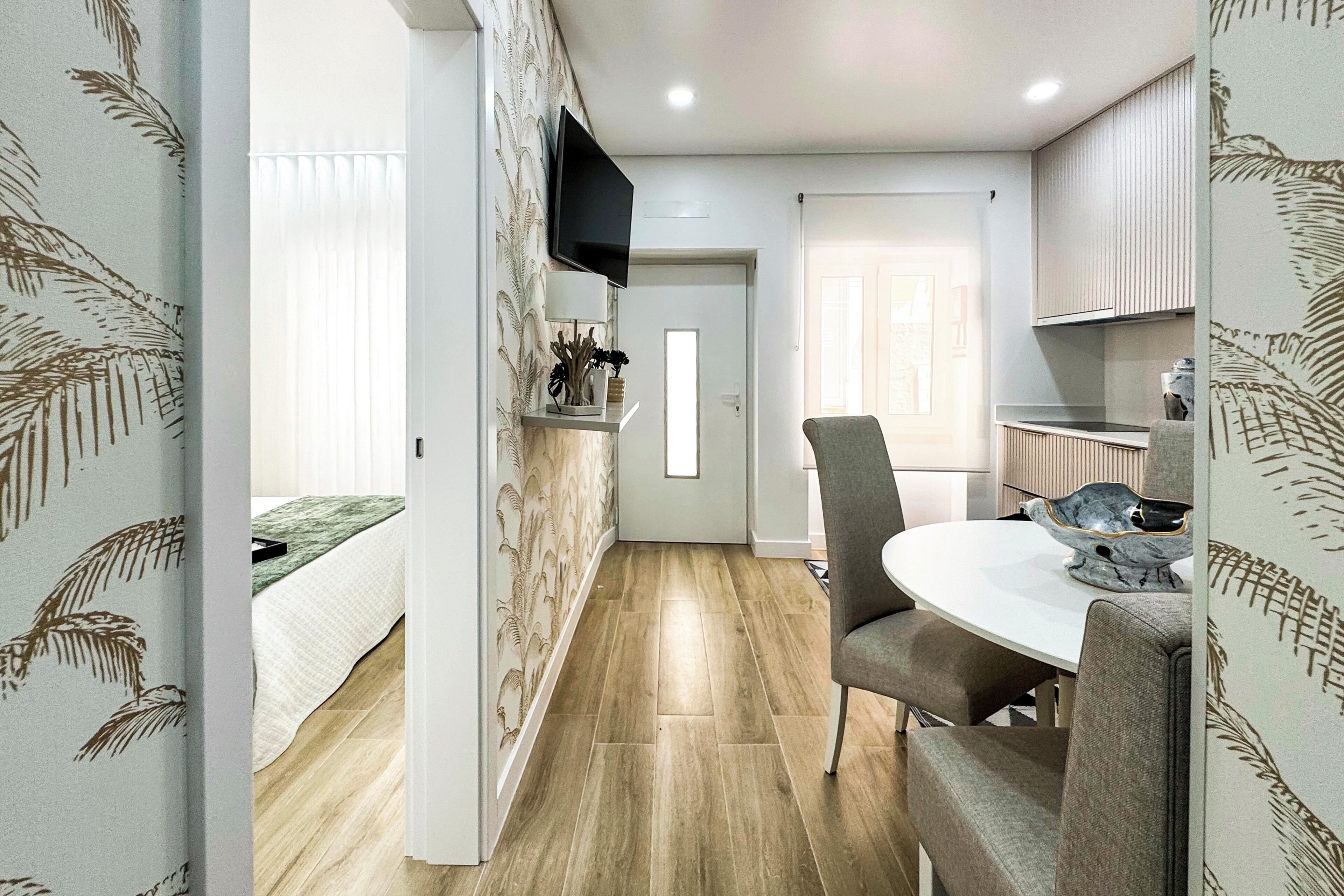 Una cucina moderna con zona pranzo, pavimento in legno e televisore a parete.
