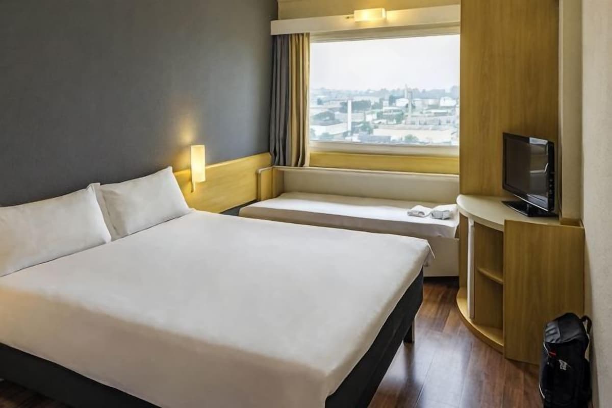 Ett hotellrum med en stor säng, en tv, ett fönster med utsikt över staden och en liten sittgrupp.