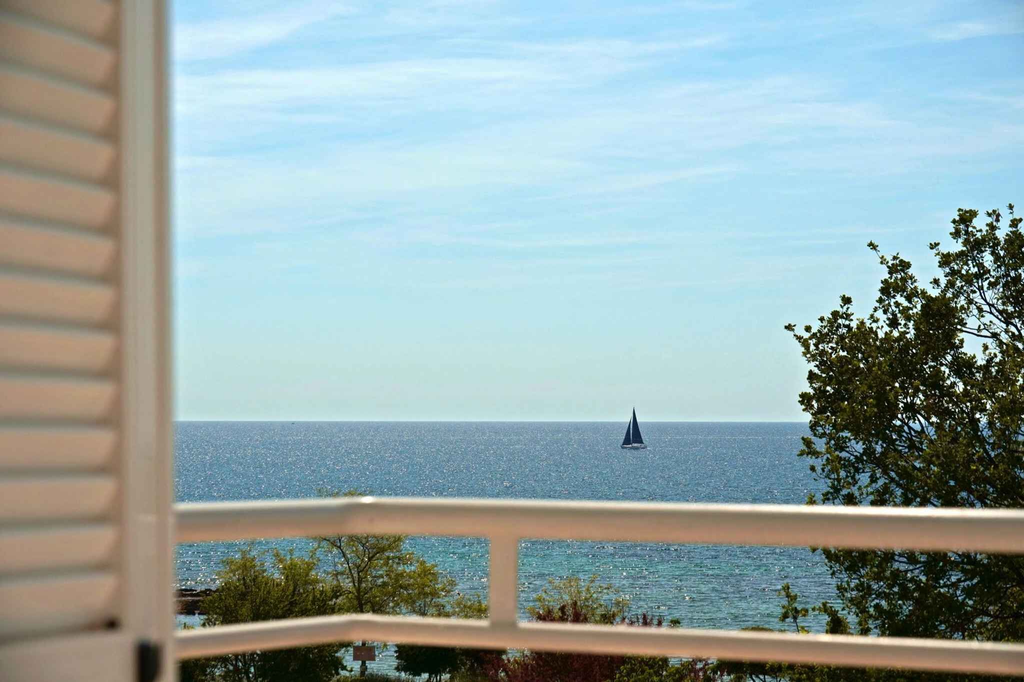 A view of the sea from a balcony with a sailboat in the distance.