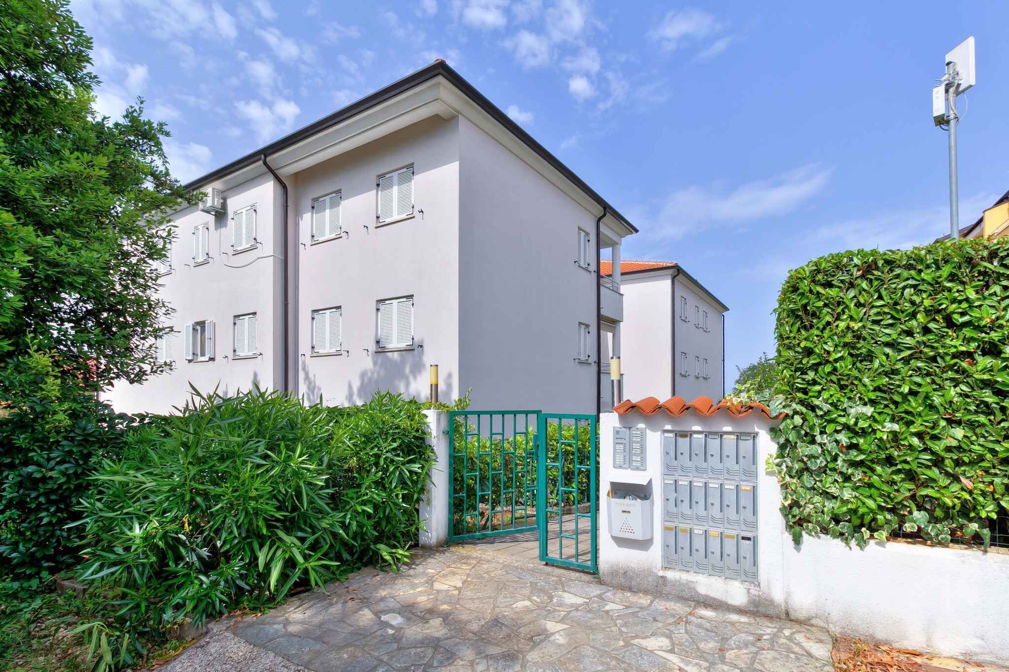 A two-story building with a white facade, a green gate, and a mailbox on the right side.