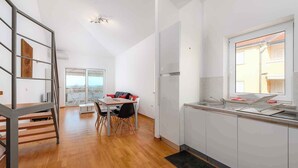 Une cuisine moderne avec des meubles blancs, un évier en acier inoxydable et une fenêtre donnant sur un paysage urbain.