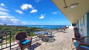 A balcony with wicker furniture, a stone floor, and a view of the ocean. - Calm, Quiet, New, & Clean Waikiki Queen Bed Studio - WAIKIKI GRAND HOTEL® 804 (Honolulu)
