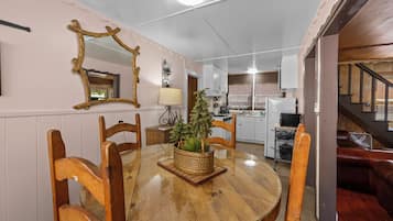 A dining area with a round wooden table, chairs, a potted plant, and a mirror on the wall.